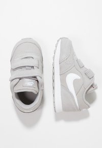 Šedé tenisky s kombinací semiše a síťoviny, s bíl�ým logem Nike, suchými zipy a texturovanou gumovou podrážkou.