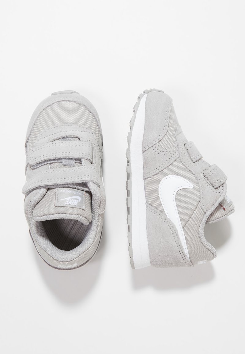 Šedé tenisky s kombinací semiše a síťoviny, s bílým logem Nike, suchými zipy a texturovanou gumovou podrážkou.