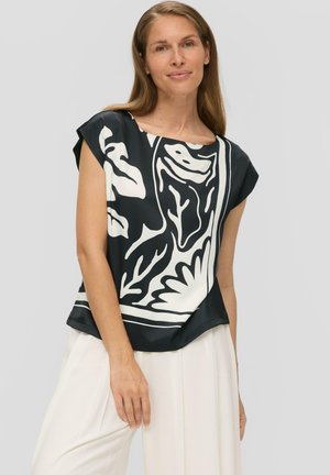 Schwarz-weiße Bluse mit Blumenmuster, Rundhalsausschnitt, kurzen Ärmeln und glatter Oberfläche, kombiniert mit hellen Hosen.