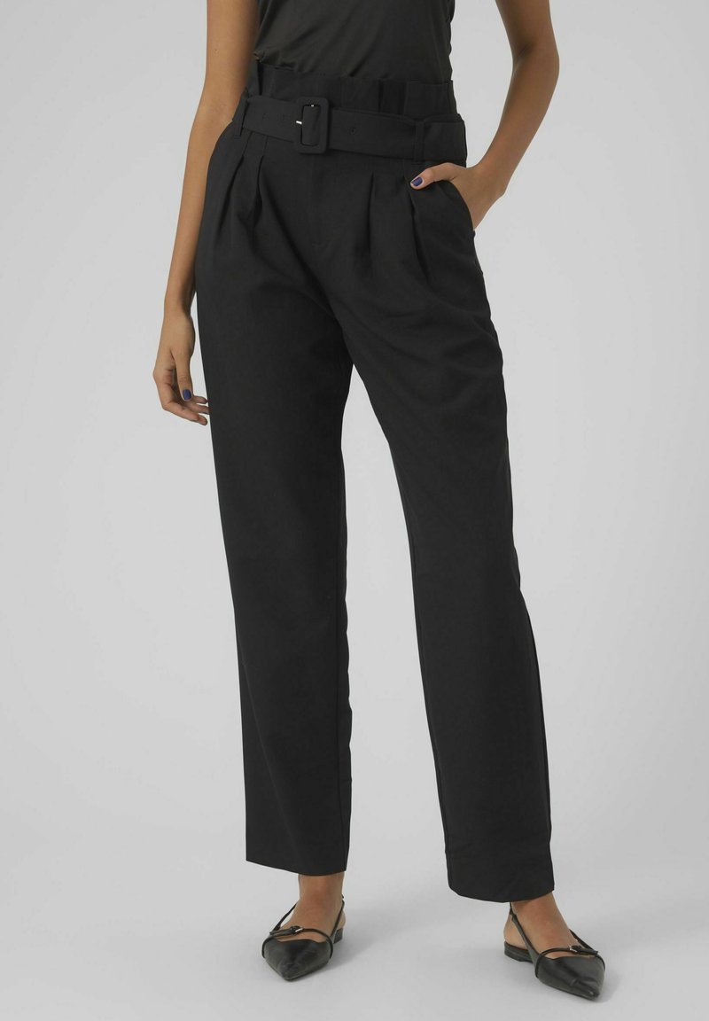 Pantalons noirs taille haute avec une jambe large, dotés d'une ceinture avec une boucle rectangulaire, de plis et de poches latérales. Texture de tissu lisse.