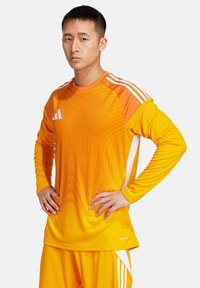 Oranges Sportlangarmshirt mit Farbverlauf und weißen Streifen auf den Schultern. Feuchtigkeitsableitender Stoff, lockerer Schnitt.