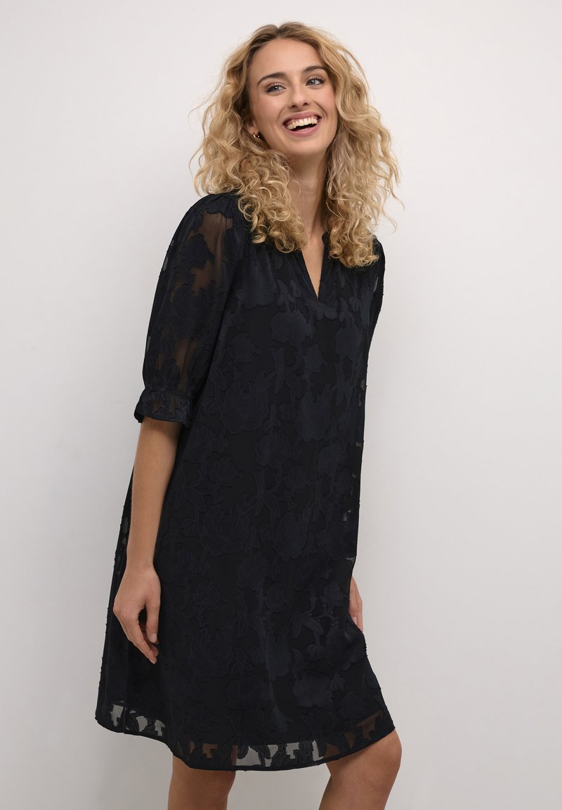 Vestito blu navy di linea con texture in pizzo floreale, scollatura a V e maniche a tre quarti, caratterizzato da una vestibilità ampia e sovrapposizione trasparente.