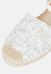 Espadrillas intrecciate bianche con accenti metallici, dotate di una punta in fibra naturale lavorata all'uncinetto e di una suola piatta in juta, che presenta una texture in rilievo.