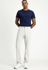 Marineblaues Kurzarm-T-Shirt kombiniert mit hellgrauen Hosen und weißen Sneakern. Lässige Passform, glattes Material und minimale Designdetails.