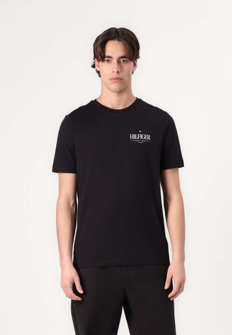 Zwarte T-shirt met korte mouwen en een ronde halslijn, voorzien van een witte "HILFIGER" logo op de borst. Gemaakt van gladde katoen stof.