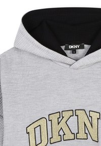 Sudadera gris texturizada con un interior ribeteado negro. Presenta un gran logo dorado de "DKNY" en la parte frontal y una capucha con cordón.