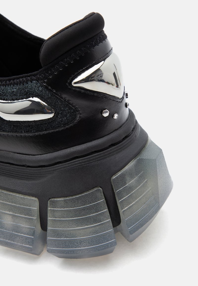Schwarzer Sneaker-Absatz mit dicker, durchsichtiger, segmentierter Sohle, metallisch silbernen Akzentformen, kleinen silbernen Nieten und texturiertem Stoffpaneel.