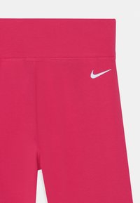 Leggings sportivi rosa con una consistenza liscia, vita alta e logo Nike bianco a sinistra.