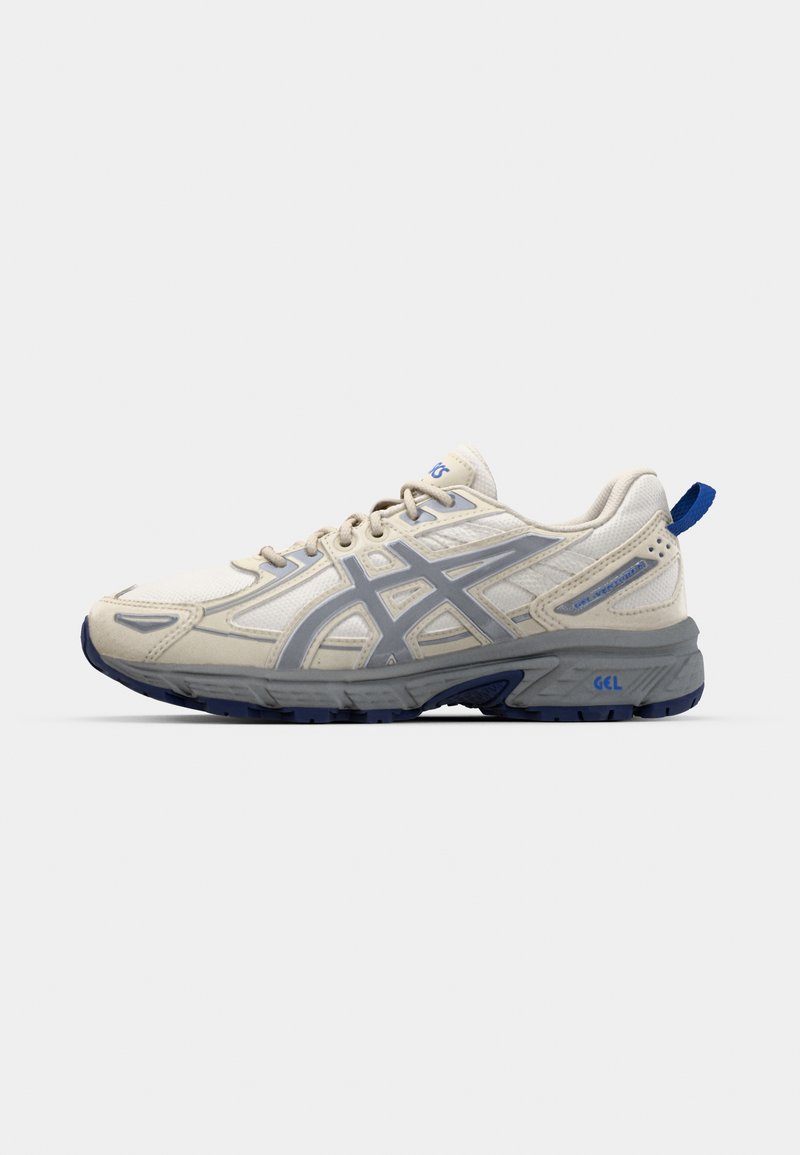 Zapatillas deportivas en malla color blanco roto con acentos en gris y azul. Las características incluyen un upper texturizado, una suela acolchada y un tirador trasero para facilitar el calzado.