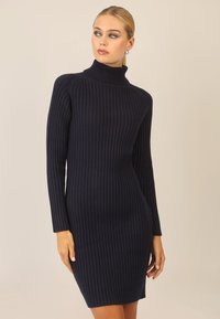 Marineblå ribbet turtleneck-kjole med lange ærmer og en tætsiddende silhuet, der har lodrette striber og en blød tekstur.