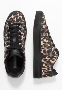 Černé a béžové sneakers s leopardím potiskem, s texturovaným svrškem, černými šňůrkami a pevným černým gumovým podešví. Minimalistický design a kulatá špička.