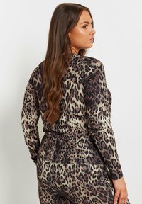 Langärmliges Oberteil mit Leopardenmuster aus weichem Stoff, mit einer figurnahen Passform, Rundhalsausschnitt und nahtlosem Design an Ärmeln und Taille.