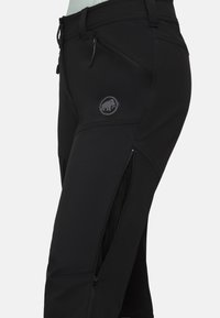Svart utomhusbyxor i stretchmaterial, med fickor som stängs med dragkedja, en logotypapplikation och en slim fit-design.