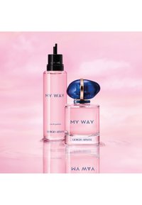 To rosa Giorgio Armani "My Way" parfymeflasker på en reflekterende overflate med en myk rosa bakgrunn.