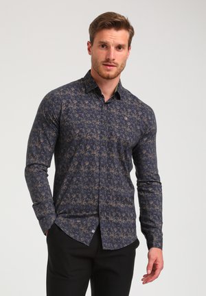 Camisa de manga larga azul marino con un diseño estampado en color beige, botones en contraste y un ajuste entallado. La textura es suave.
