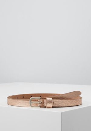Thin metallic rose gold leather belt with silver metal buckle resting coiled on a white surface against a plain light gray background.