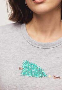 Sivá mikina s grafikou ozdobeného vianočného stromčeka a psa v santovskej čiapke, v hravých farbách a kreslenom štýle.