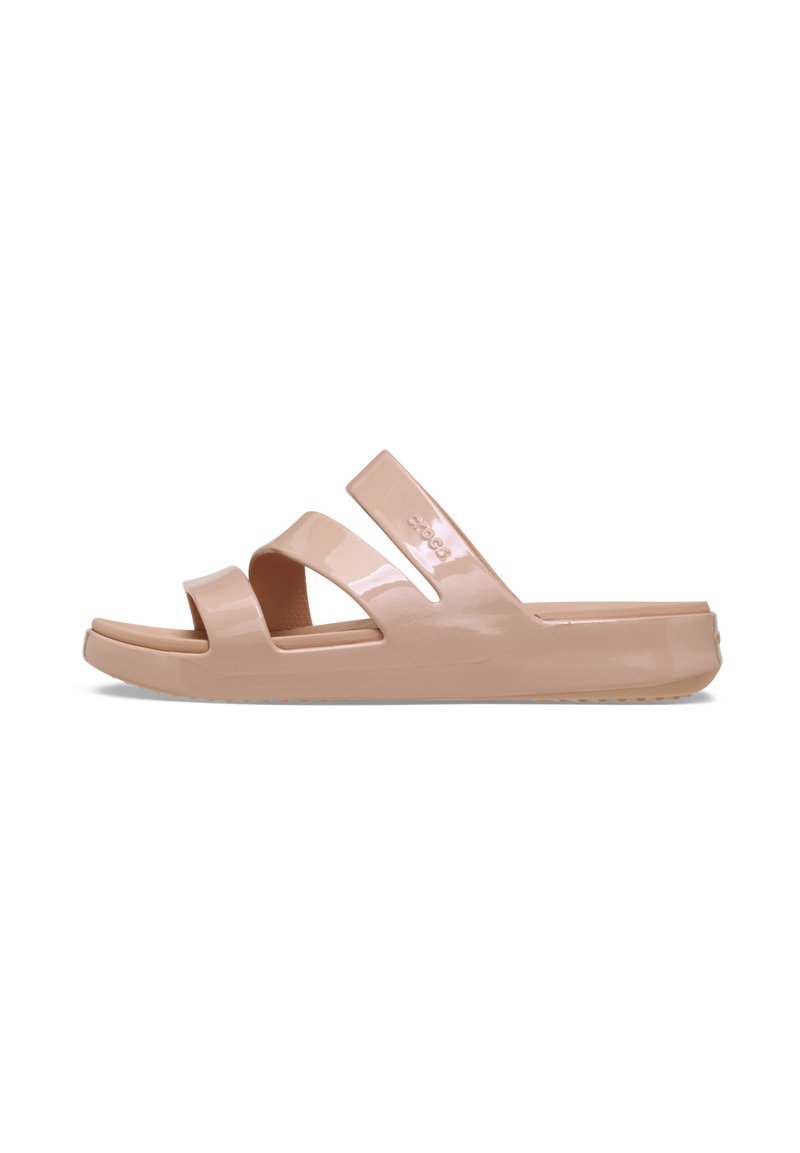 Pale pink slide sandals made of glossy material, featuring two wide, overlapping straps and a textured sole for grip.