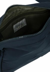 Marineblå stofpose med lynlåslukning; indvendigt med grøn foring og en ekstra lynlåslomme. Mærket læser "camel active."