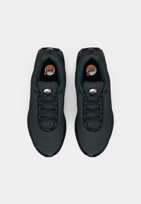 Black athletic shoes with a textured upper, featuring a rounded toe, visible lacing, and rubber soles. Logo accents on tongue.