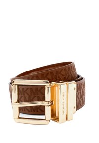 Ruskea Michael Kors -vö ja kullanvärinen solki, jossa on toistuva MK-logo kuvioituna hihnaan, käärittynä valkoista taustaa vasten.