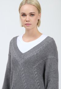 Grauer gestrickter Pullover mit V-Ausschnitt und Kabelstrickmuster. Verfügt über gerippte Bündchen und Saum, strukturierter Stoff und eine lockere Passform.