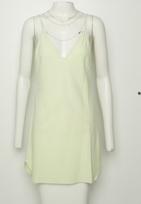 Robe sans manches vert clair avec fines bretelles et col en V, présentée sur un mannequin blanc sur un fond uni.