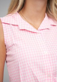 Rosa gingham-ærmeløs bluse med krave, der har knapdetaljer foran og en glat, let stofstruktur.