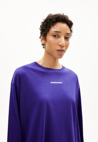 Lilanes Langarmshirt aus weichem Stoff, mit Rundhalsausschnitt und dem weißen Text "ARMEDANGELS", der mittig auf der Brust platziert ist.