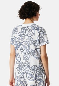 Kurzarm-T-Shirt mit einem blau-weißen Muster aus runden Designs mit Sternen, aus einem weichen Stoff mit glatter Textur gefertigt.