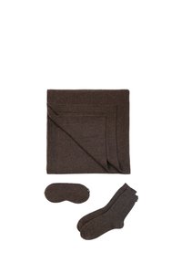 Couverture en laine marron avec un masque de sommeil et des chaussettes assortis. Texture douce, forme rectangulaire et design minimaliste. Chaque article présente des détails de motifs subtils.