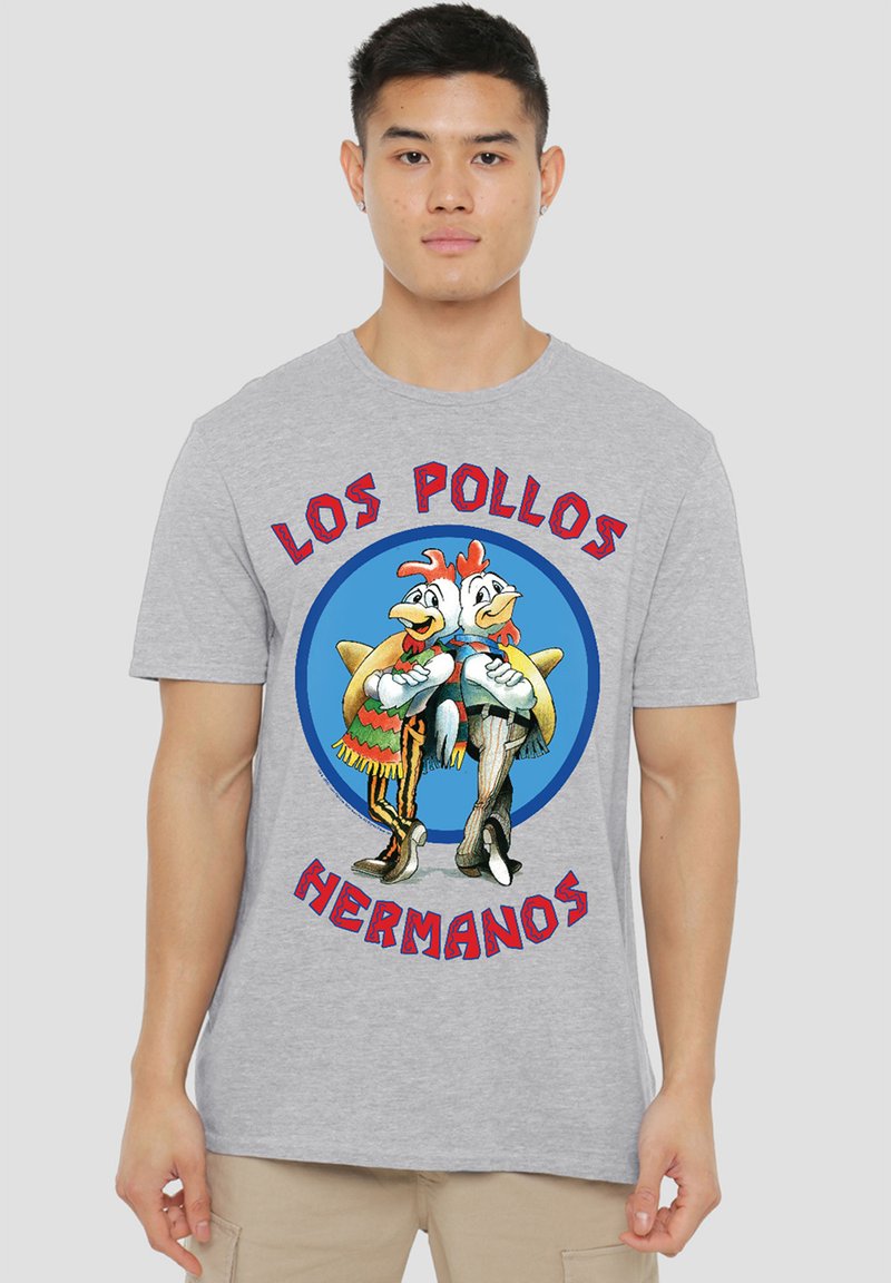 Graues T-Shirt mit cartoonhaften Hühnern in bunten Outfits und dem Text "LOS POLLOS HERMANOS", der einen blauen grafischen Hintergrund umkreist.