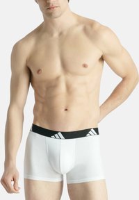 Vita boxer briefs med en svart midja som har tre vita ränder. Tyget ser slätt och stretchigt ut med en tight passform.