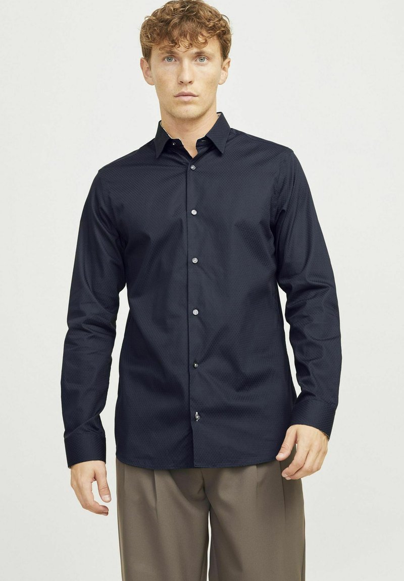 Camicia da uomo a maniche lunghe, di colore blu scuro, con un motivo sottile, colletto button-down e vestibilità slim. Presenta bottoni trasparenti e una texture del tessuto liscia.