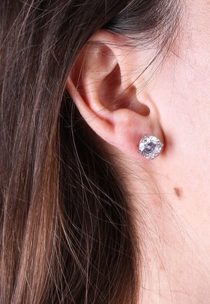 Boucles d'oreilles rondes en argent présentant une grande pierre précieuse transparente sertie dans un métal argenté. Le design est simple avec quatre griffes.