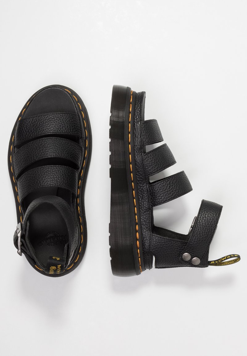 Black leather sandals with three wide straps, textured surface, and an adjustable buckle. Accented with orange stitching and a thick sole.