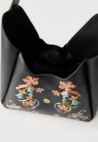 Μαύρη δερμάτινη τσάντα χειρός με πολύχρωμα κεντητά λουλουδένια σχέδια και μαγνητικό κούμπωμα, με ανοιχτό εσωτερικό που δείχνει το λογότυπο "Just Cavalli".