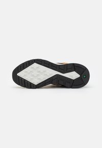 Gumová podešev s texturovaným černým designem, bílá mezipodešev a charakteristický vzor pro zajištění trakce. Obsahuje branding Timberland.