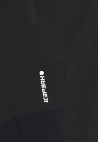 Shorts de sport noirs avec un tissu texturé, une poche latérale et un logo de la marque blanc. Finition lisse avec des détails de couture contrastés.