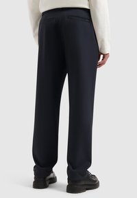 Marineblauwe broek van glad weefsel met een rechte pijpdesign, voorzien van twee achterzakken en een subtiele logotag op de tailleband.