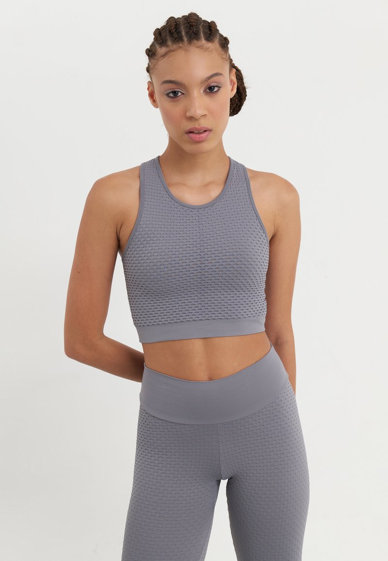 Ljust grå aktivkläder-set som består av en texturerad crop top med rund hals och matchande högmidjade leggings, båda med ett bikupemönster.