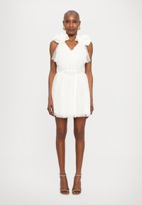 Witte mini-jurk met doorzichtige ruches en bloemmotieven op de schouders, en een getailleerde taille. Glad uitgangsmateriaal met gelaagde textuur.