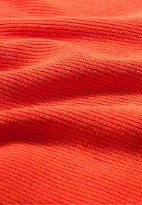 Tessuto strutturato di un profondo arancione con un motivo a righe. Superficie morbida con lievi variazioni di tonalità, che creano profondità visiva. Adatto per abbigliamento.