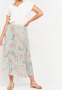 Lightweight, short-sleeve white top with a front zipper and a pastel paisley-patterned, flowy skirt featuring beige elastic waistband and sandals.