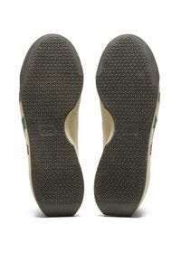 Suole delle scarpe con una texture in gomma. Presentano prese circolari e un bordo superiore liscio. Motivo grigio testurizzato su una base beige chiaro.