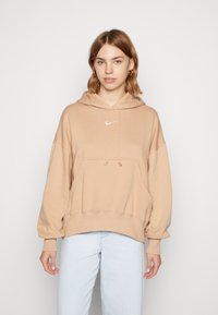 Sweatshirt bege com capuz, bolso canguru, bainha e punhos canelados, apresentando um pequeno logótipo Nike branco no peito.
