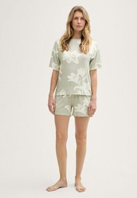 Conjunto de loungewear floral en verde claro que incluye una camiseta de manga corta y pantalones cortos a juego. Tejido suave con un ajuste relajado y una textura sutil.