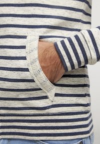 Maglietta a maniche lunghe a righe con strisce orizzontali in blu navy e grigio chiaro, texture morbida e taschino frontale con finitura a taglio vivo.