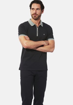 Schwarzes Polohemd mit Reißverschluss am Kragen, mit kontrastierendem hellgrünen Saum an Ärmeln und Kragen. Glatte Textur, lässige Passform, minimales Logodetail.