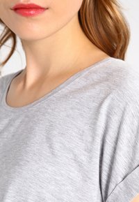 Svetlosivý, krátky rukáv, tričko vyrobené z mäkkej, hladkej tkaniny s okrúhlym výstrihom a jemnou textúrou.